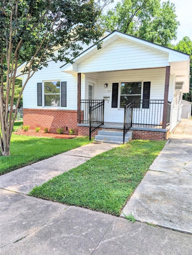 922 Ratcliff St, Shreveport, LA 71104 - bungalow-style house with a front lawn, a porch, brick siding, and driveway