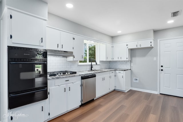 2869 Alkay Dr, Shreveport, LA 71118 - kitchen with appliances with stainless steel finishes, a warming drawer, under cabinet range hood, decorative backsplash, and wood finished floors