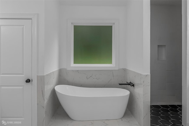 231 Ramsey, Stonewall, LA 71078 - bathroom featuring marble finish flooring, a soaking tub, a wainscoted wall, and tile walls
