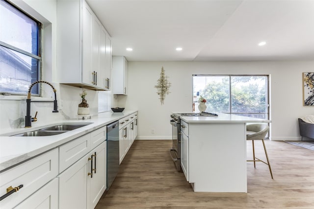 806 Brookshire Cir, Garland, TX 75043 - kitchen with stainless steel appliances, a sink, a breakfast bar area, light countertops, and light wood-type flooring