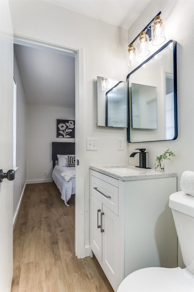 806 Brookshire Cir, Garland, TX 75043 - bathroom featuring vanity, wood finished floors, toilet, and baseboards