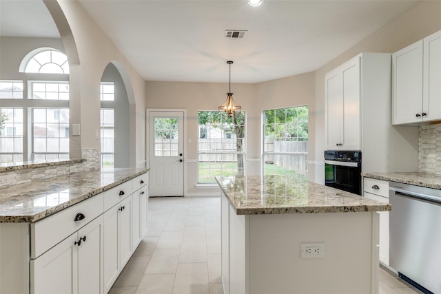 5312 Bellis Dr, Fort Worth, TX 76244 - kitchen with stainless steel dishwasher, black oven, arched walkways, a kitchen island, and backsplash