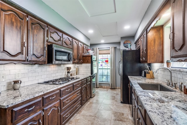 1520 Papeete Dr, Plano, TX 75075 - kitchen featuring appliances with stainless steel finishes, a sink, tasteful backsplash, light stone countertops, and dark brown cabinets