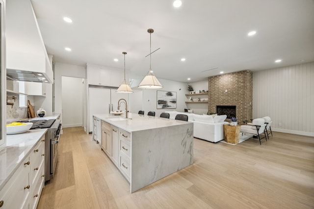 6244 Richmond Ave, Dallas, TX 75214 - kitchen with high end range, custom range hood, a sink, light wood-style flooring, and white cabinetry