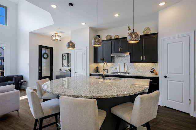 363 Somerville Dr, Mckinney, TX 75071 - kitchen with a sink, light stone countertops, a breakfast bar area, tasteful backsplash, and under cabinet range hood