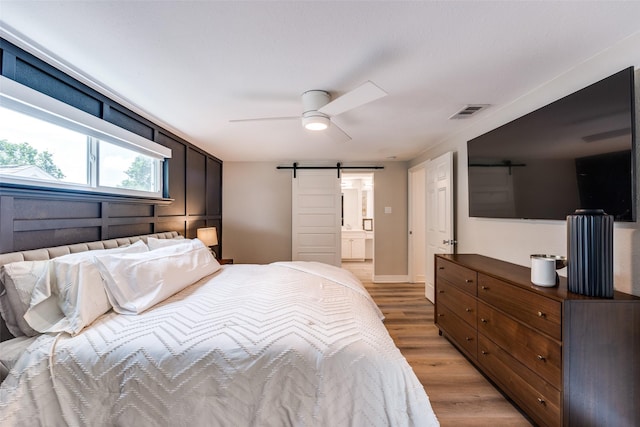 2617 Beechmont Dr, Dallas, TX 75228 - bedroom with a barn door, light wood-style floors, a ceiling fan, and connected bathroom