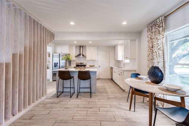 2617 Beechmont Dr, Dallas, TX 75228 - kitchen with wall chimney range hood, appliances with stainless steel finishes, light countertops, white cabinetry, and a center island