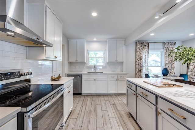 2617 Beechmont Dr, Dallas, TX 75228 - kitchen with appliances with stainless steel finishes, wall chimney range hood, a sink, decorative backsplash, and light wood-type flooring