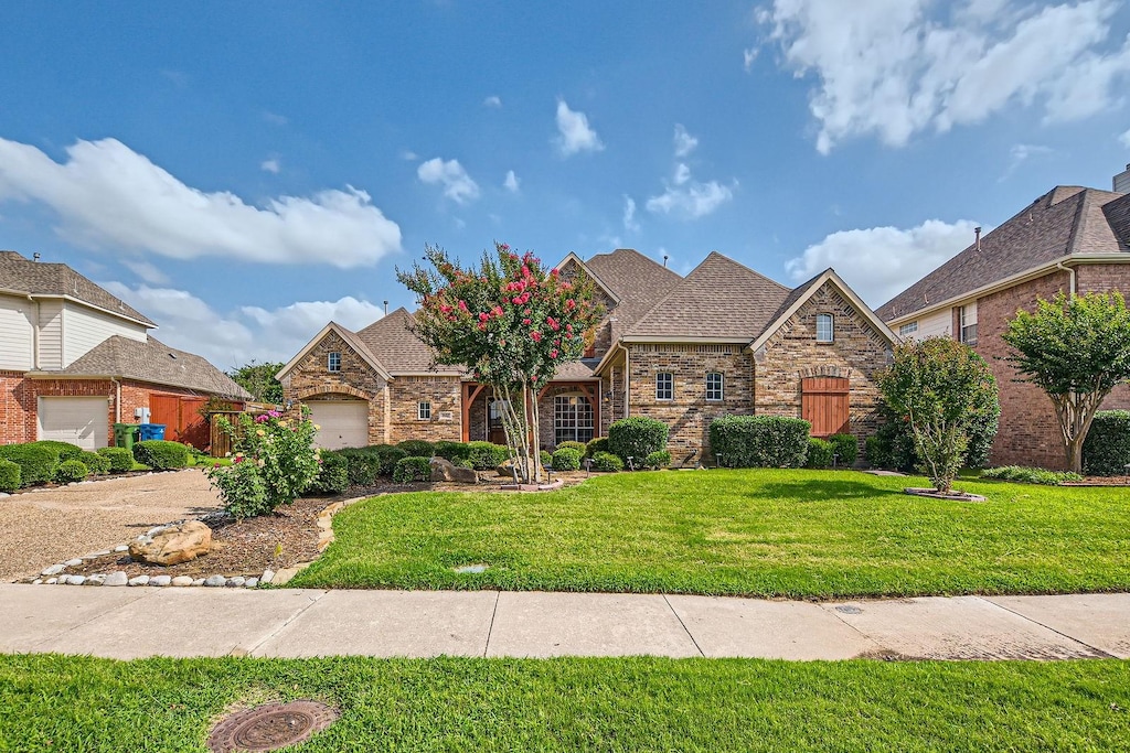 1633 Coyote Rdg, Carrollton, TX 75010 - view of front facade featuring a front yard, brick siding, roof with shingles, and a garage