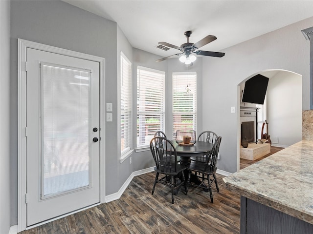 4710 Ashley Cir, Midlothian, TX 76065 - dining space with dark wood-type flooring, a ceiling fan, arched walkways, and a fireplace