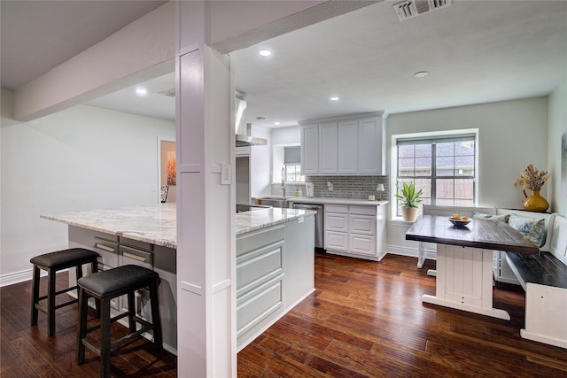 1220 Melony Dr, Sulphur Springs, TX 75482 - kitchen with stainless steel dishwasher, a kitchen bar, healthy amount of natural light, dark wood finished floors, and recessed lighting
