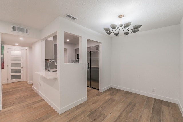 4851 Cedar Springs Rd Unit 175, Dallas, TX 75219 - hall with a chandelier, light wood-style floors, baseboards, a sink, and recessed lighting
