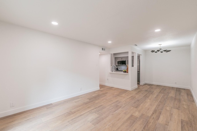 4851 Cedar Springs Rd Unit 175, Dallas, TX 75219 - unfurnished living room featuring recessed lighting, baseboards, light wood finished floors, a chandelier, and a sink