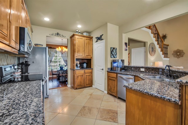 156 Buckskin Dr, Van Alstyne, TX 75495 - kitchen featuring appliances with stainless steel finishes, a chandelier, dark stone counters, brown cabinets, and light tile patterned flooring
