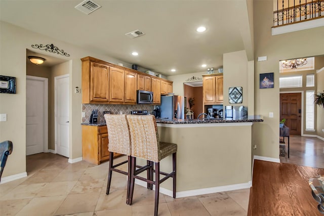 156 Buckskin Dr, Van Alstyne, TX 75495 - kitchen with stainless steel appliances, dark stone counters, a kitchen bar, decorative backsplash, and recessed lighting
