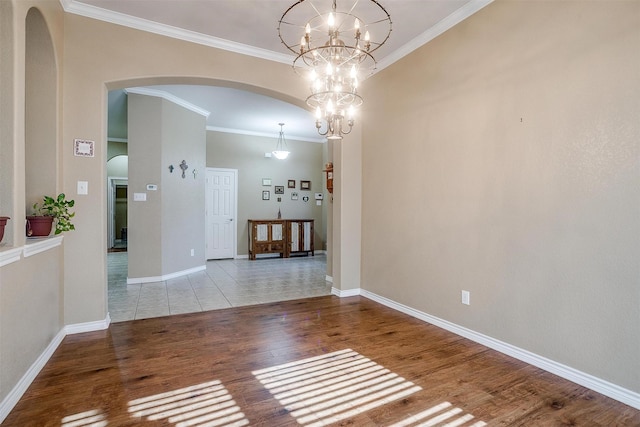 2134 Lorrie Ln, Weatherford, TX 76087 - empty room featuring arched walkways, wood finished floors, ornamental molding, baseboards, and a chandelier