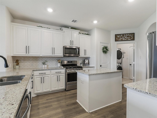 505 Maverick St, Anna, TX 75409 - kitchen with stainless steel appliances, a sink, estacked washer and dryer, white cabinetry, and backsplash