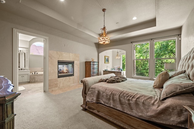 609 Deerwood Ln, Keller, TX 76248 - bedroom with carpet floors, arched walkways, recessed lighting, a tiled fireplace, and a tray ceiling
