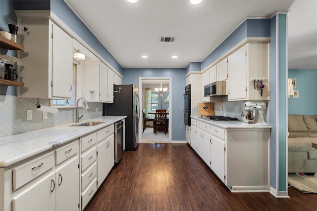 2118 Wooded Acres Dr, Waco, TX 76710 - kitchen featuring a sink, stainless steel appliances, dark wood finished floors, white cabinetry, and ornamental molding
