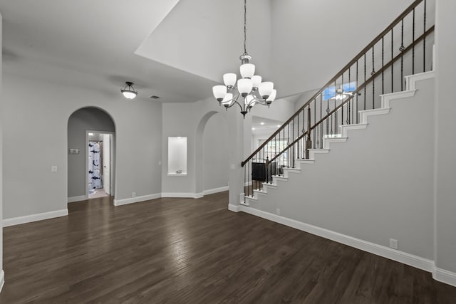 612 Wildriver Trl, Fort Worth, TX 76131 - unfurnished living room with arched walkways, dark wood-type flooring, stairs, baseboards, and a towering ceiling