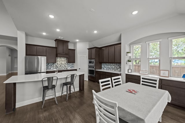 612 Wildriver Trl, Fort Worth, TX 76131 - kitchen with stainless steel appliances, a center island with sink, dark brown cabinetry, tasteful backsplash, and arched walkways