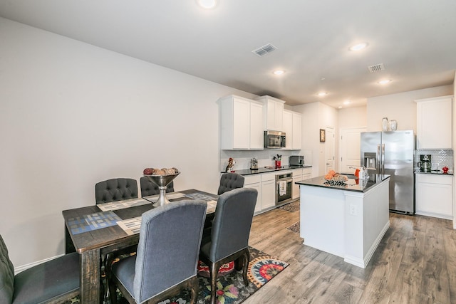 1129 Rusk Way, Lewisville, TX 75077 - kitchen with appliances with stainless steel finishes, dark countertops, light wood-type flooring, white cabinetry, and recessed lighting