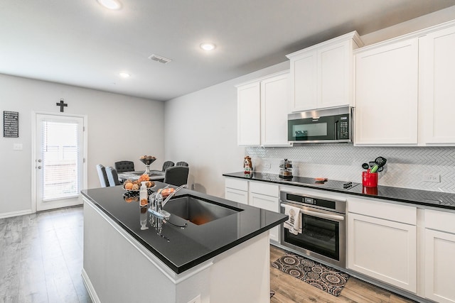 1129 Rusk Way, Lewisville, TX 75077 - kitchen featuring stainless steel appliances, a sink, light wood-style floors, dark countertops, and recessed lighting