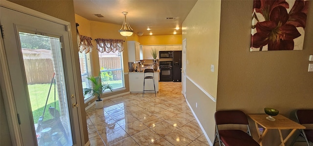 5632 Centeridge Dr, Dallas, TX 75249 - kitchen featuring black appliances, white cabinets, light marble finish flooring, baseboards, and hanging light fixtures