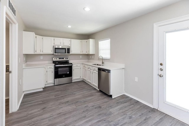 527 English Oak Dr, Allen, TX 75002 - kitchen featuring appliances with stainless steel finishes, a sink, white cabinets, wood finished floors, and light countertops