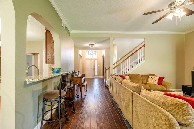 4406 Westcreek Ln, Sachse, TX 75048 - living room with arched walkways, crown molding, ceiling fan, dark wood-type flooring, and a textured ceiling