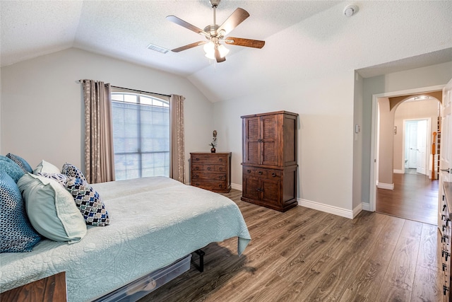 4406 Westcreek Ln, Sachse, TX 75048 - bedroom with arched walkways, lofted ceiling, wood finished floors, a textured ceiling, and baseboards