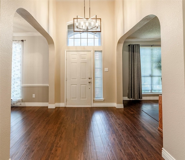4406 Westcreek Ln, Sachse, TX 75048 - foyer with arched walkways, crown molding, plenty of natural light, dark wood-style flooring, and a textured wall
