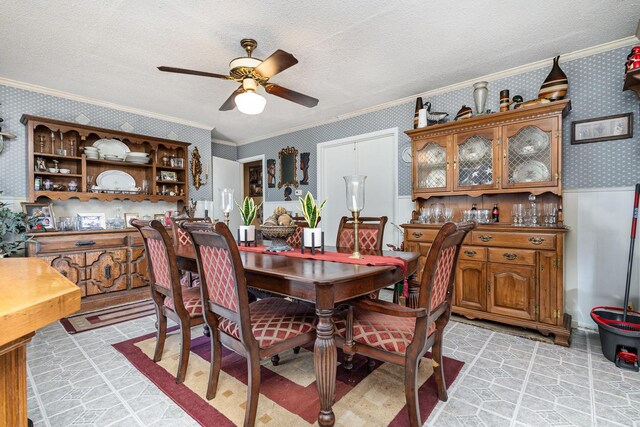 2530 Robin Ln, Garland, TX 75041 - dining room featuring wallpapered walls, crown molding, a ceiling fan, a textured ceiling, and a wainscoted wall
