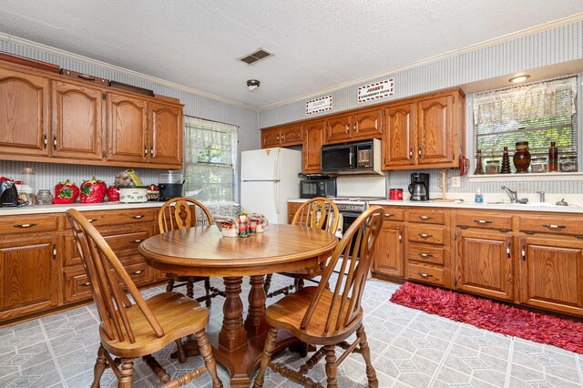 2530 Robin Ln, Garland, TX 75041 - kitchen featuring black microwave, ornamental molding, freestanding refrigerator, a textured ceiling, and brown cabinets