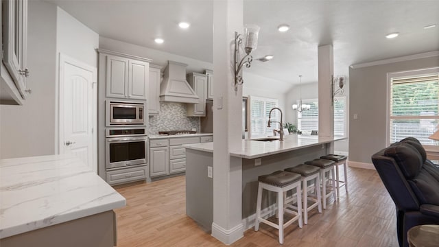 1530 Petaluma Dr, Rockwall, TX 75087 - kitchen featuring stainless steel appliances, a sink, custom range hood, a breakfast bar area, and healthy amount of natural light