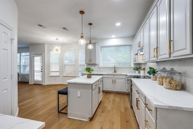 5031 Enclave Ct, Mckinney, TX 75072 - kitchen featuring a sink, electric range, light wood-type flooring, tasteful backsplash, and a kitchen breakfast bar