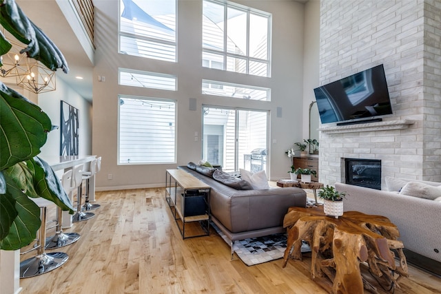 1328 Madeline Pl Unit B, Fort Worth, TX 76107 - living area featuring a brick fireplace, light wood-style floors, a high ceiling, baseboards, and a chandelier
