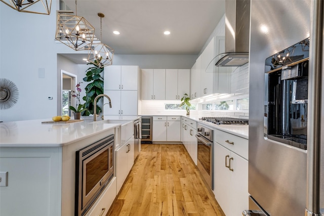 1328 Madeline Pl Unit B, Fort Worth, TX 76107 - kitchen featuring wall chimney range hood, stainless steel appliances, wine cooler, a sink, and a chandelier