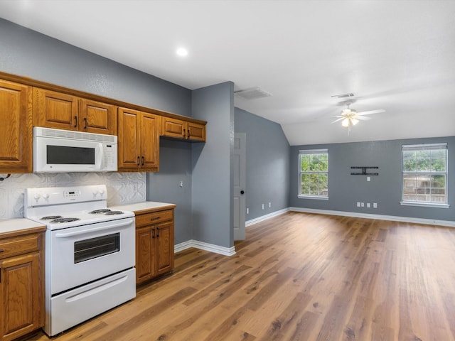 9120 Timber Oaks Dr, Fort Worth, TX 76179 - kitchen with white appliances, brown cabinets, lofted ceiling, open floor plan, and light wood-type flooring