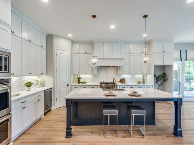 8542 Gerbera Daisy Rd, Frisco, TX 75035 - kitchen with wine cooler, decorative backsplash, light wood-type flooring, a kitchen bar, and recessed lighting