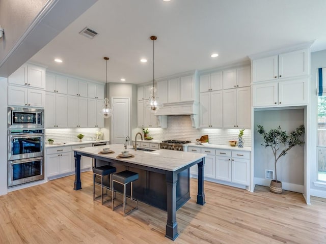 8542 Gerbera Daisy Rd, Frisco, TX 75035 - kitchen featuring appliances with stainless steel finishes, tasteful backsplash, white cabinetry, a breakfast bar area, and light wood-style flooring