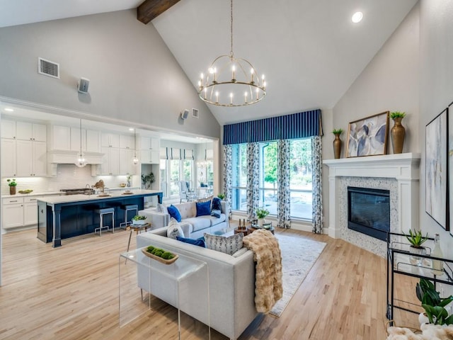 8542 Gerbera Daisy Rd, Frisco, TX 75035 - living room with high vaulted ceiling, beam ceiling, a chandelier, a stone fireplace, and light wood-style floors