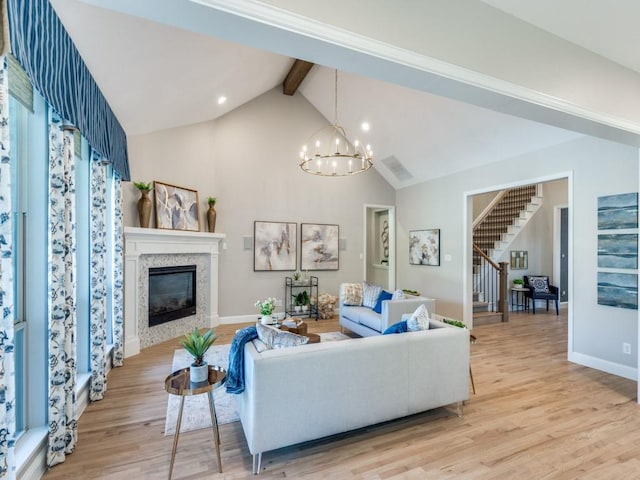 8542 Gerbera Daisy Rd, Frisco, TX 75035 - living area with beam ceiling, stairs, light wood-style floors, a glass covered fireplace, and a chandelier