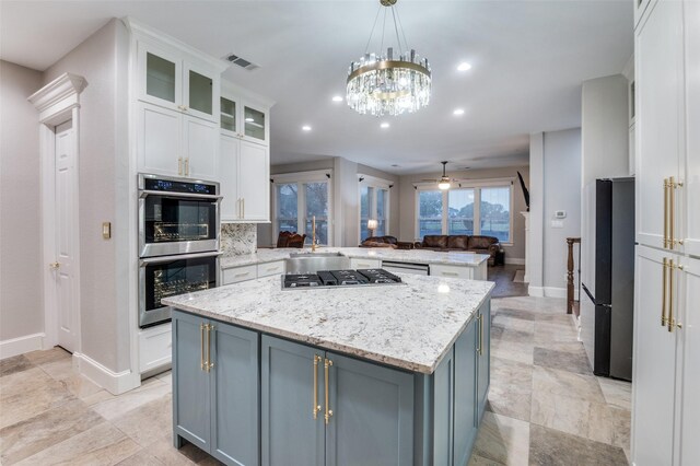 253 Bayne Rd, Haslet, TX 76052 - kitchen featuring a chandelier, appliances with stainless steel finishes, arched walkways, blue cabinets, and white cabinets