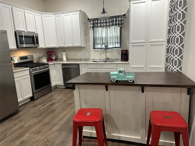 819 Beech St, Bonham, TX 75418 - kitchen featuring appliances with stainless steel finishes, a sink, dark wood-type flooring, a breakfast bar area, and white cabinets