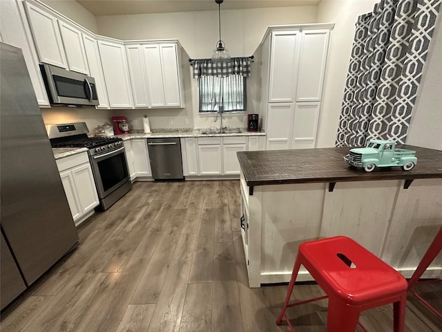 819 Beech St, Bonham, TX 75418 - kitchen featuring appliances with stainless steel finishes, wood finished floors, and white cabinets