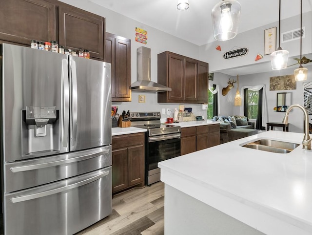 401 S 2nd St, Wortham, TX 76693 - kitchen featuring appliances with stainless steel finishes, wall chimney range hood, a sink, light countertops, and light wood-style floors