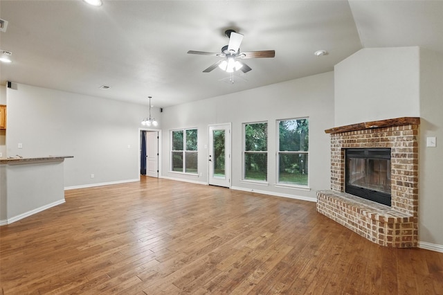 8109 County Road 804, Burleson, TX 76028 - unfurnished living room featuring a ceiling fan, light wood-style floors, a brick fireplace, and a chandelier