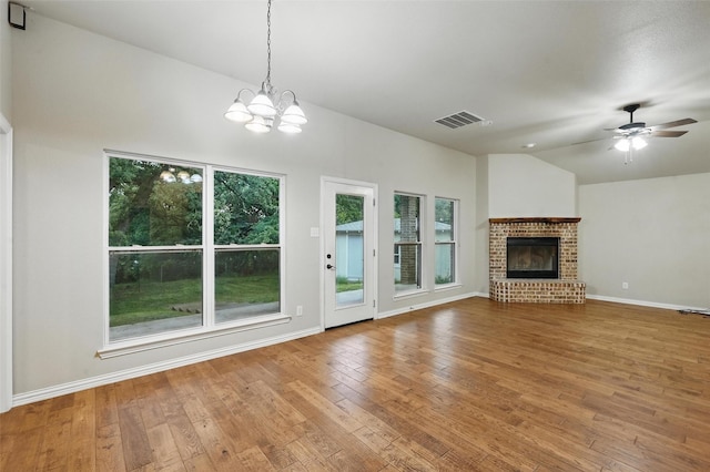 8109 County Road 804, Burleson, TX 76028 - unfurnished living room featuring hardwood / wood-style flooring, a brick fireplace, a chandelier, lofted ceiling, and a ceiling fan