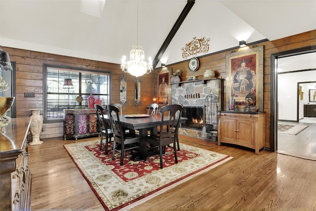 161 Cheyenne Dr, Nocona, TX 76255 - dining room with lofted ceiling, wood walls, a chandelier, wood finished floors, and a stone fireplace